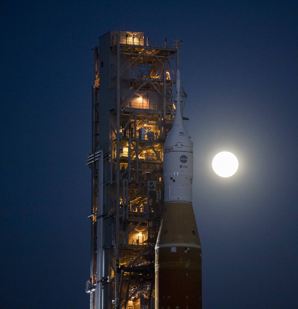 Earth's Moon is seen rising behind NASA’s Space Launch System (SLS) rocket with the Orion spacecraft aboard atop a mobile launcher as it rolls out to Launch Complex 39B for the first time, Thursday, March 17, 2022, at NASA’s Kennedy Space Center in Florida. Ahead of the Artemis I flight test, the fully stacked and integrated SLS rocket and Orion spacecraft will undergo a wet dress rehearsal to verify systems and practice countdown procedures for the first launch.