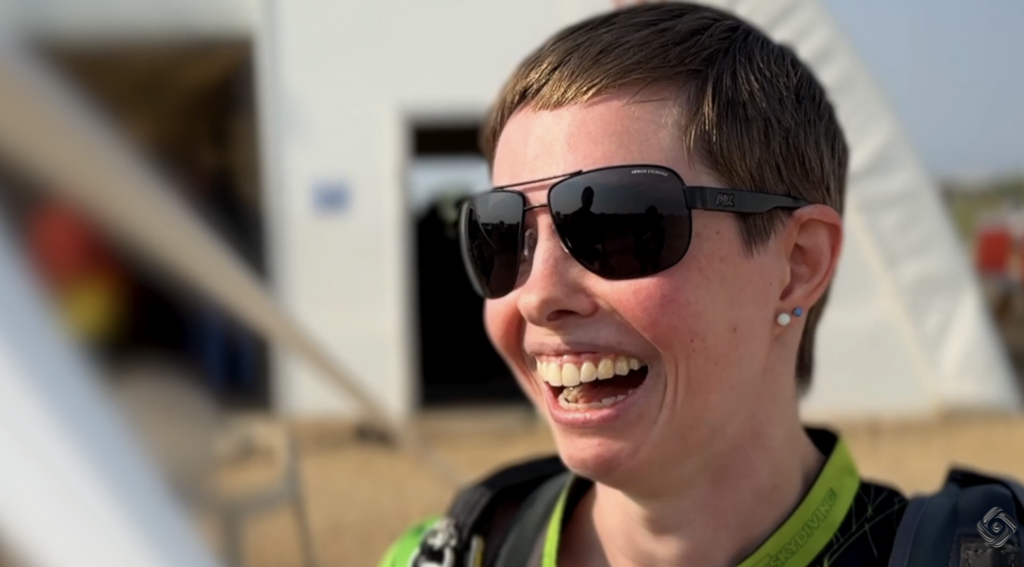 Michelle Osborne laughing and wearing sunglasses outdoors near a tent-like structure